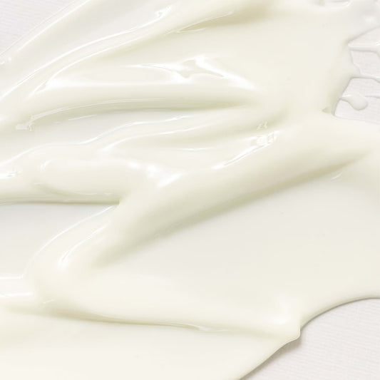 Close-up of the pale cream texture of Beauty of Joseon Relief Sun : Rice + Probiotics SPF50+ PA++++ spread across a light surface