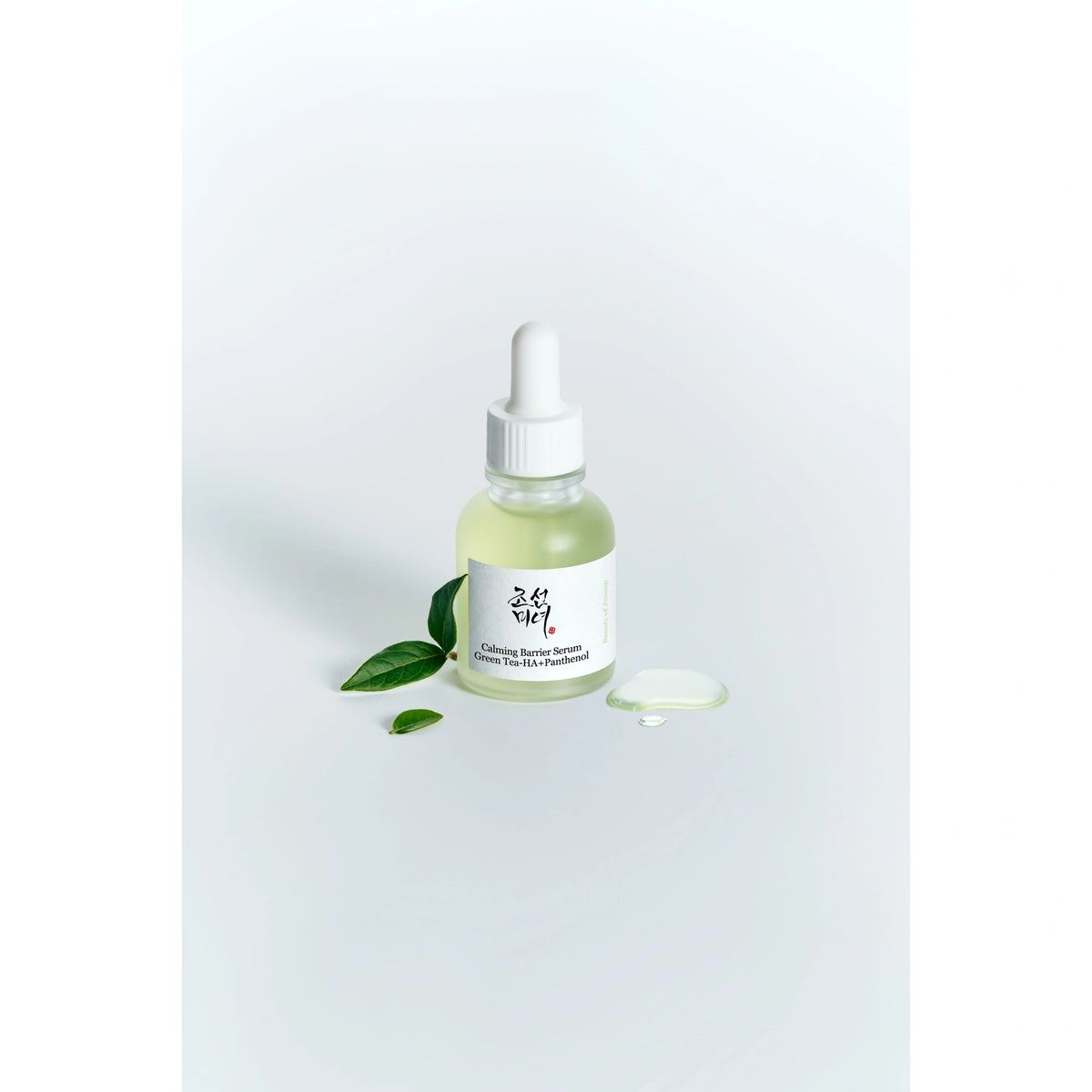 Beauty of Joseon Calming Barrier Serum 30ml bottle styled with fresh green tea leaves and a serum drop on white