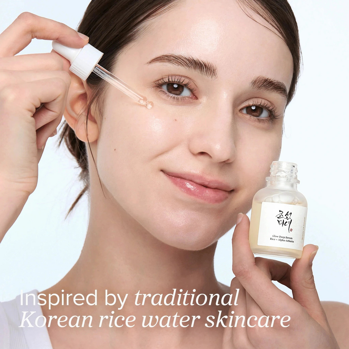 Beauty of Joseon Glow Deep Serum Rice + Alpha-Arbutin 30ml dropper being applied to model's cheek, in-use view