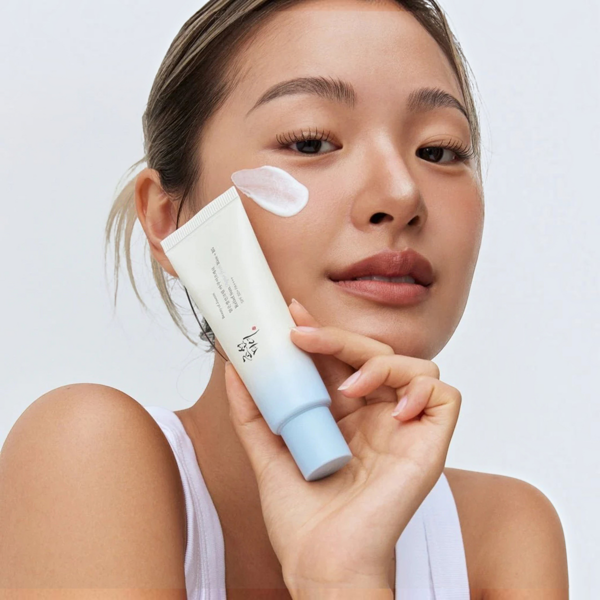Beauty of Joseon Relief Sun Aqua-Fresh Rice + B5 50ml sunscreen applied to a model's cheek, tube held in hand